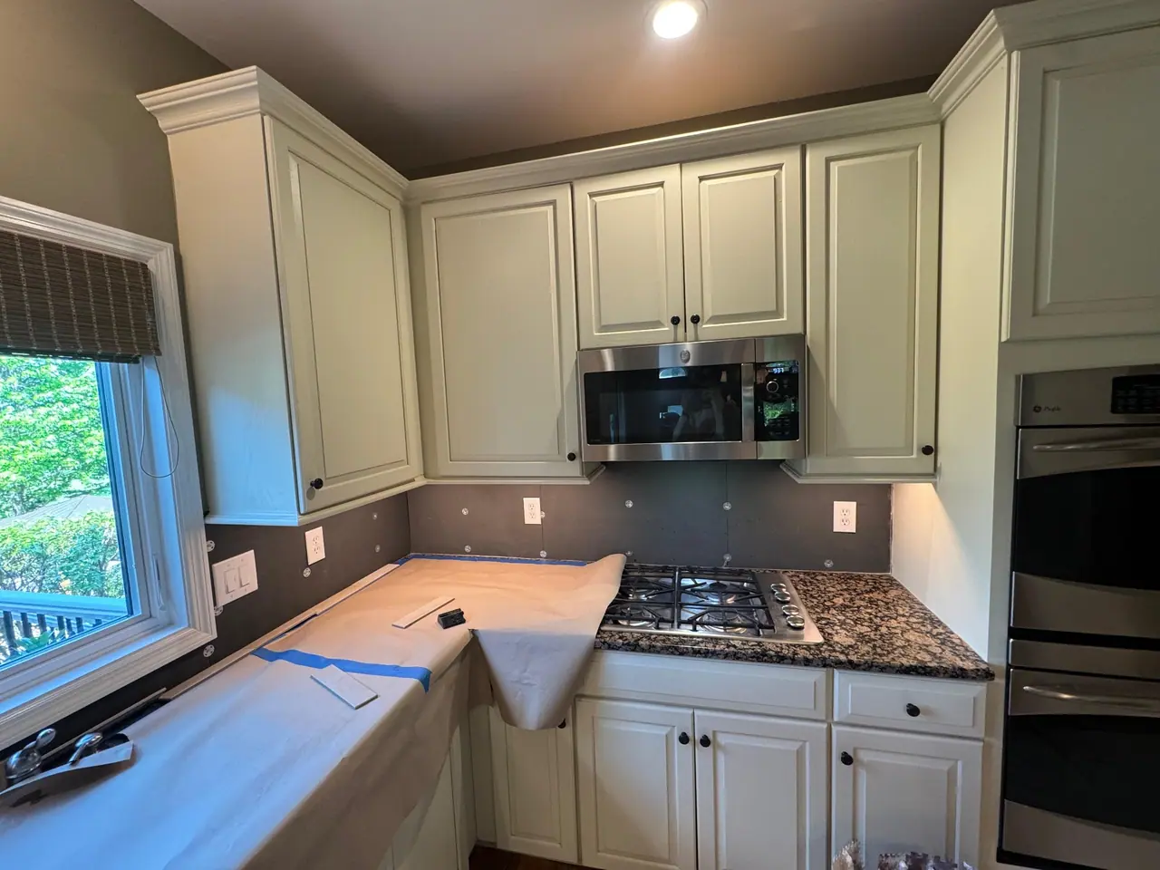 Full kitchen backsplash installation — natural stone subway tile with granite countertops and marble island. — 2