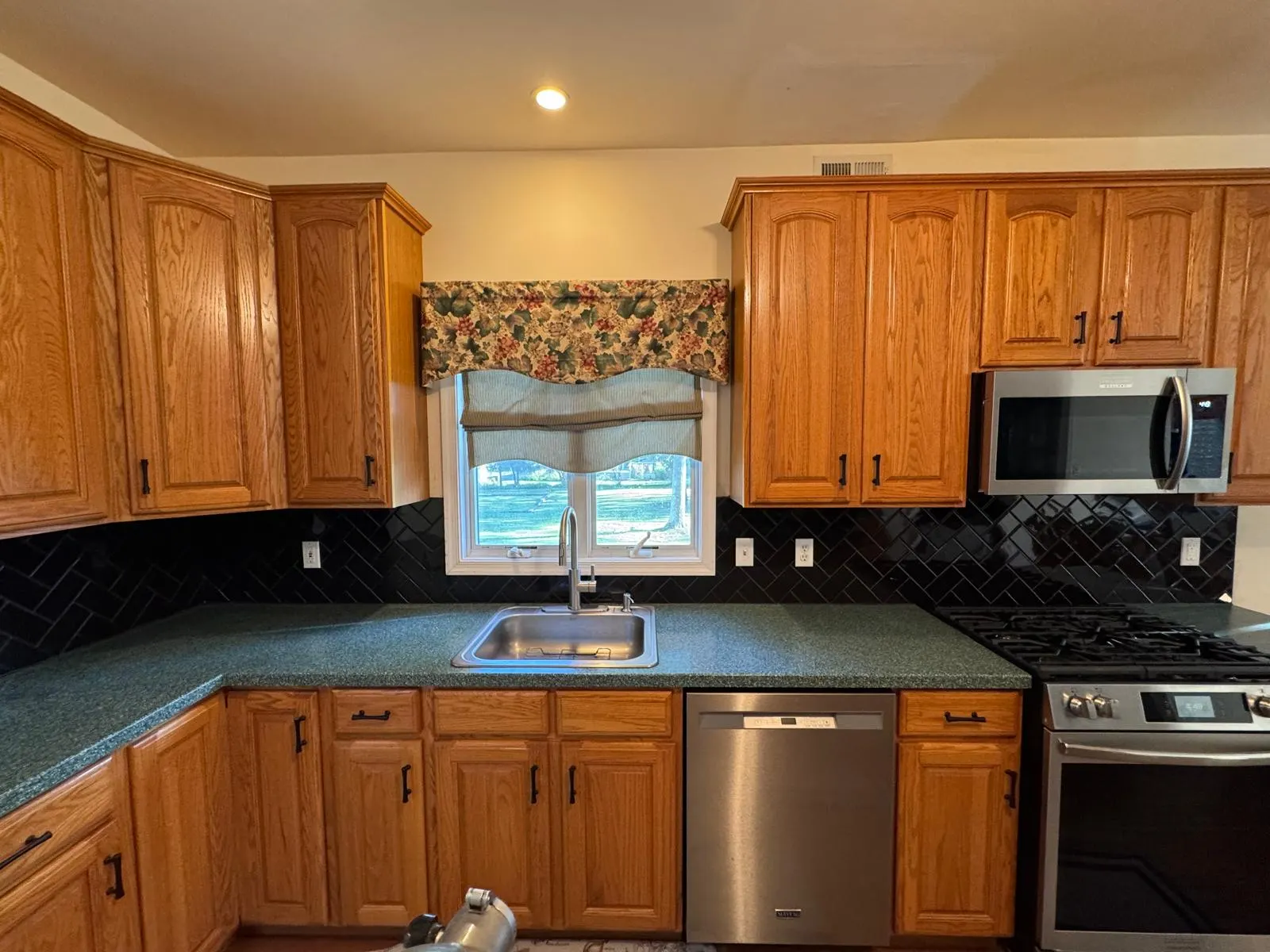 Full kitchen backsplash transformation — glossy black ceramic subway tile in herringbone pattern with crisp grout lines. — 2
