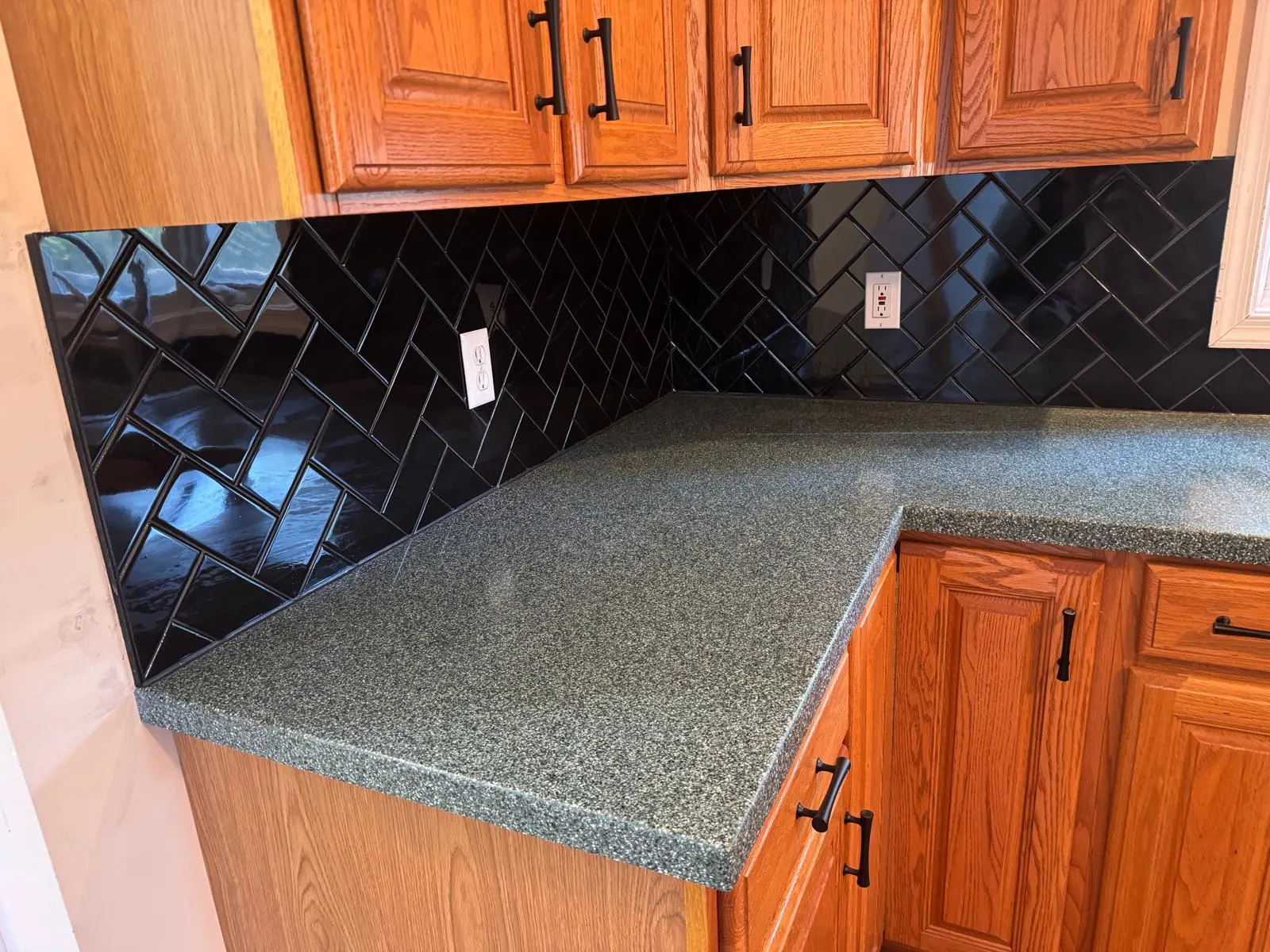 Full kitchen backsplash transformation — glossy black ceramic subway tile in herringbone pattern with crisp grout lines. — 3