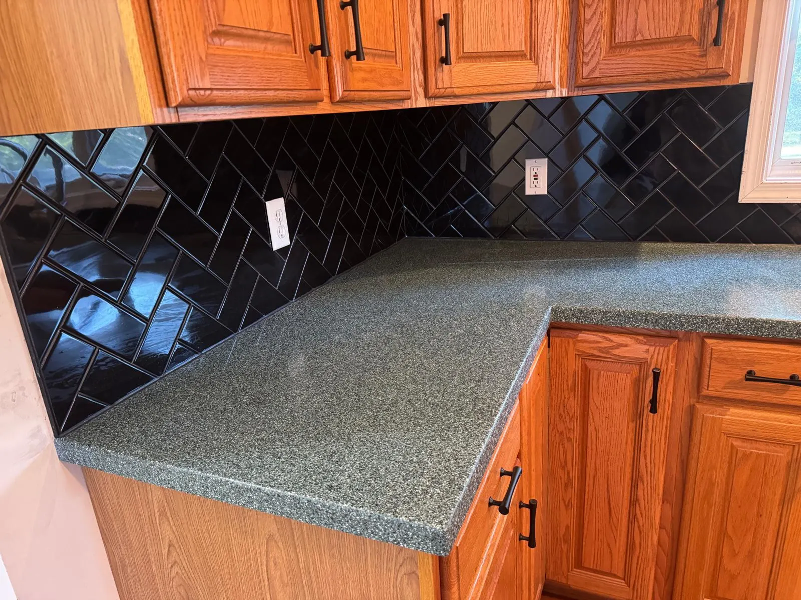 Full kitchen backsplash transformation — glossy black ceramic subway tile in herringbone pattern with crisp grout lines. — 4