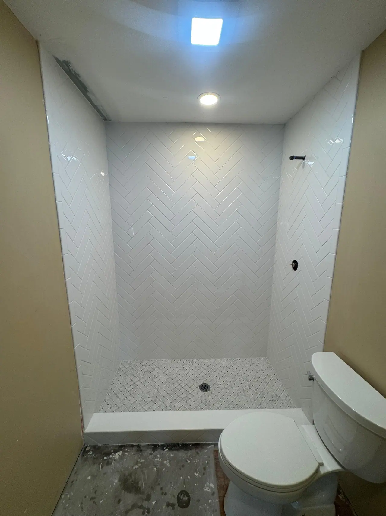 Full shower build — waterproof membrane, white herringbone subway walls, and a marble-look mosaic floor. — 2
