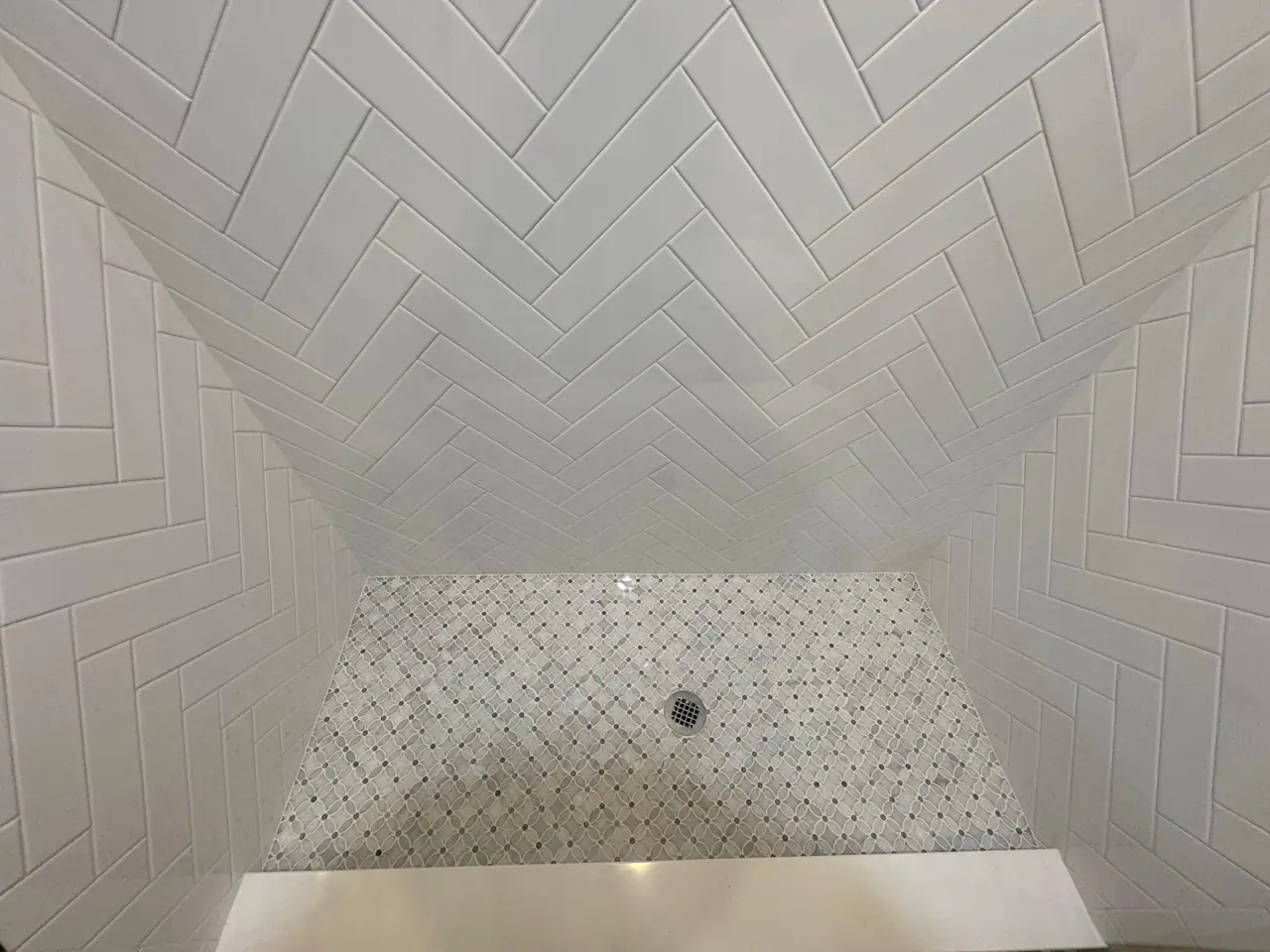 Full shower build — waterproof membrane, white herringbone subway walls, and a marble-look mosaic floor. — 4
