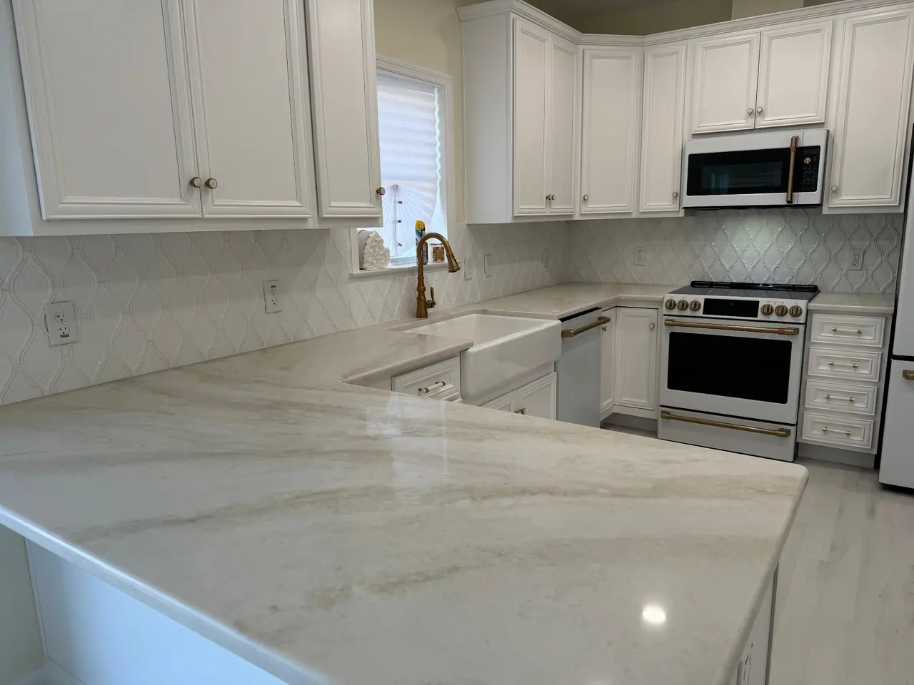 Arabesque-pattern ceramic backsplash with quartzite countertops and brushed brass hardware. — 1