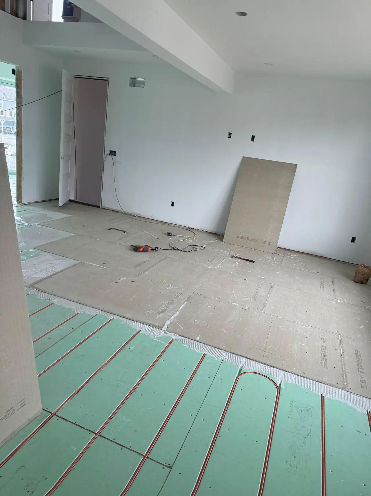 Full main floor build — radiant heating system, cement backer board prep, and large-format polished porcelain tile with waterfront views. — 1