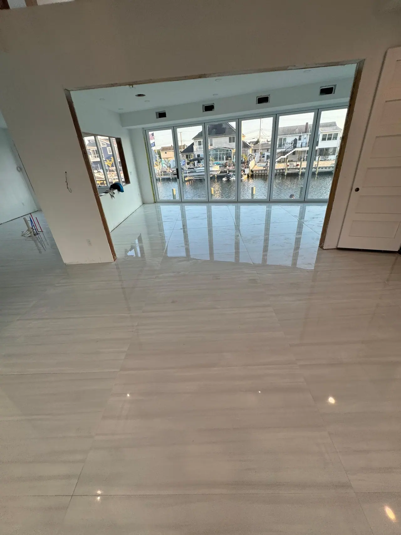 Full main floor build — radiant heating system, cement backer board prep, and large-format polished porcelain tile with waterfront views. — 8