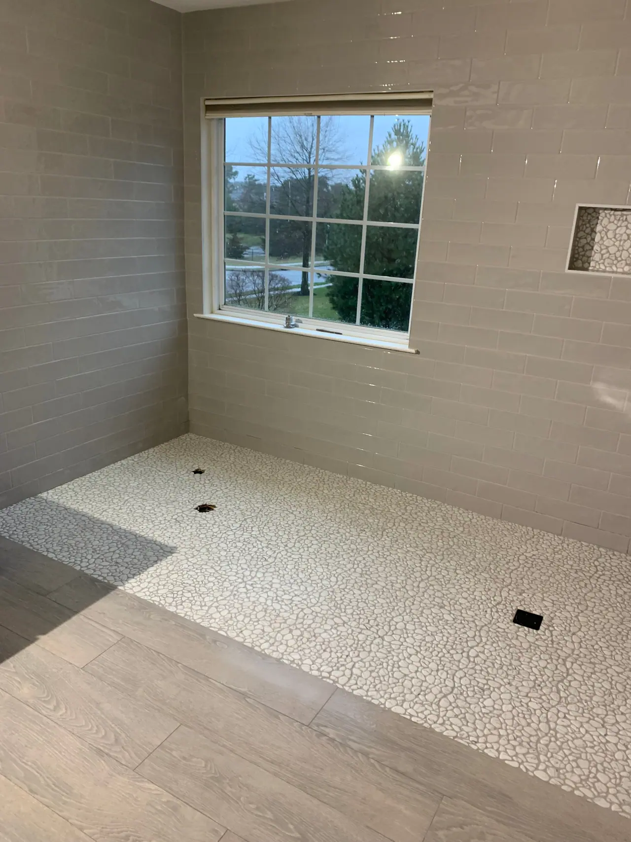 Walk-in shower with subway wall tile, pebble mosaic floor, and recessed niche detail. — 3