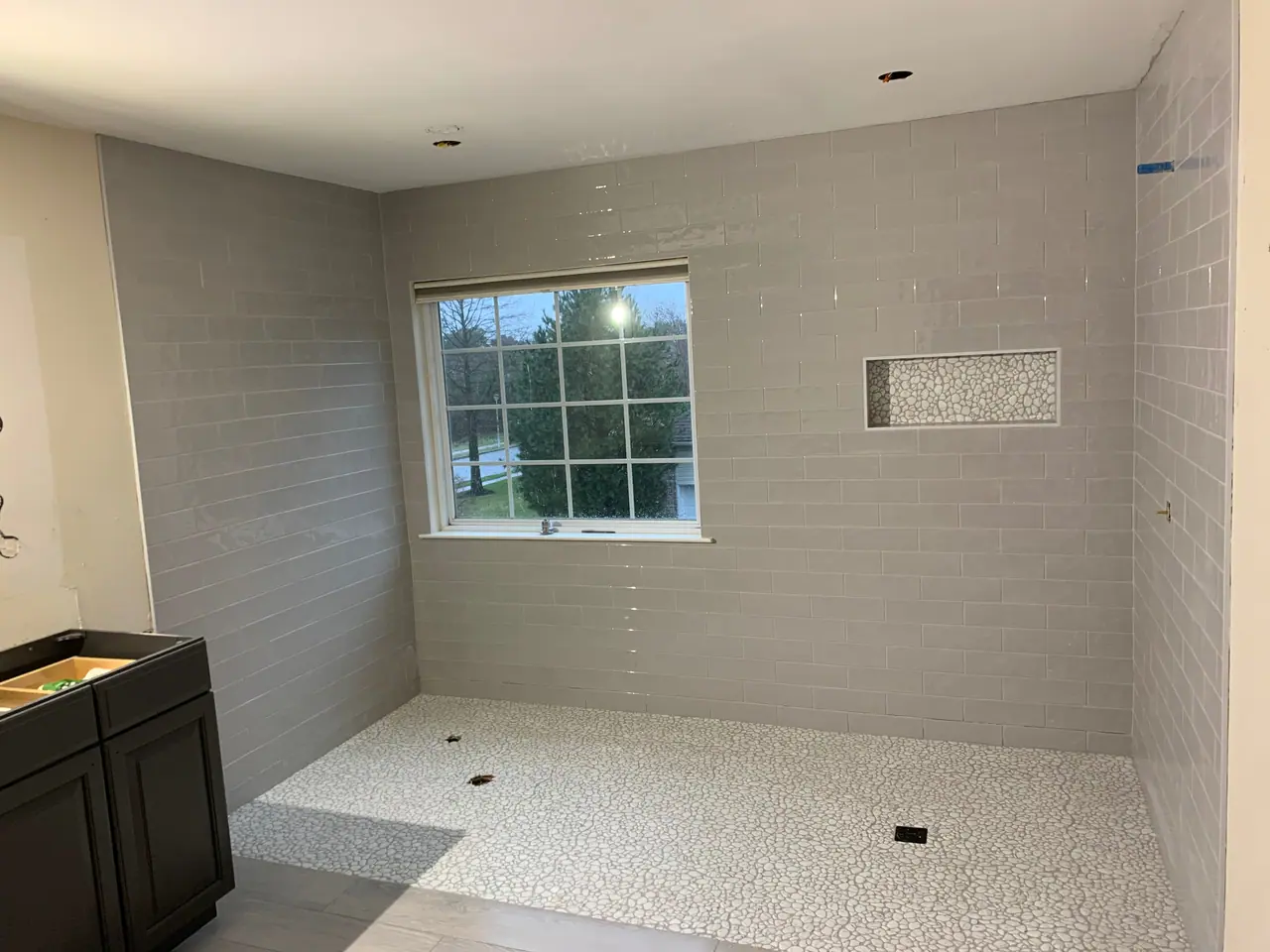 Walk-in shower with subway wall tile, pebble mosaic floor, and recessed niche detail. — 1