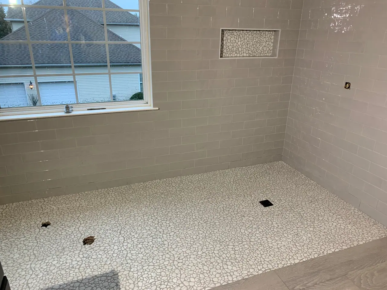 Walk-in shower with subway wall tile, pebble mosaic floor, and recessed niche detail. — 4