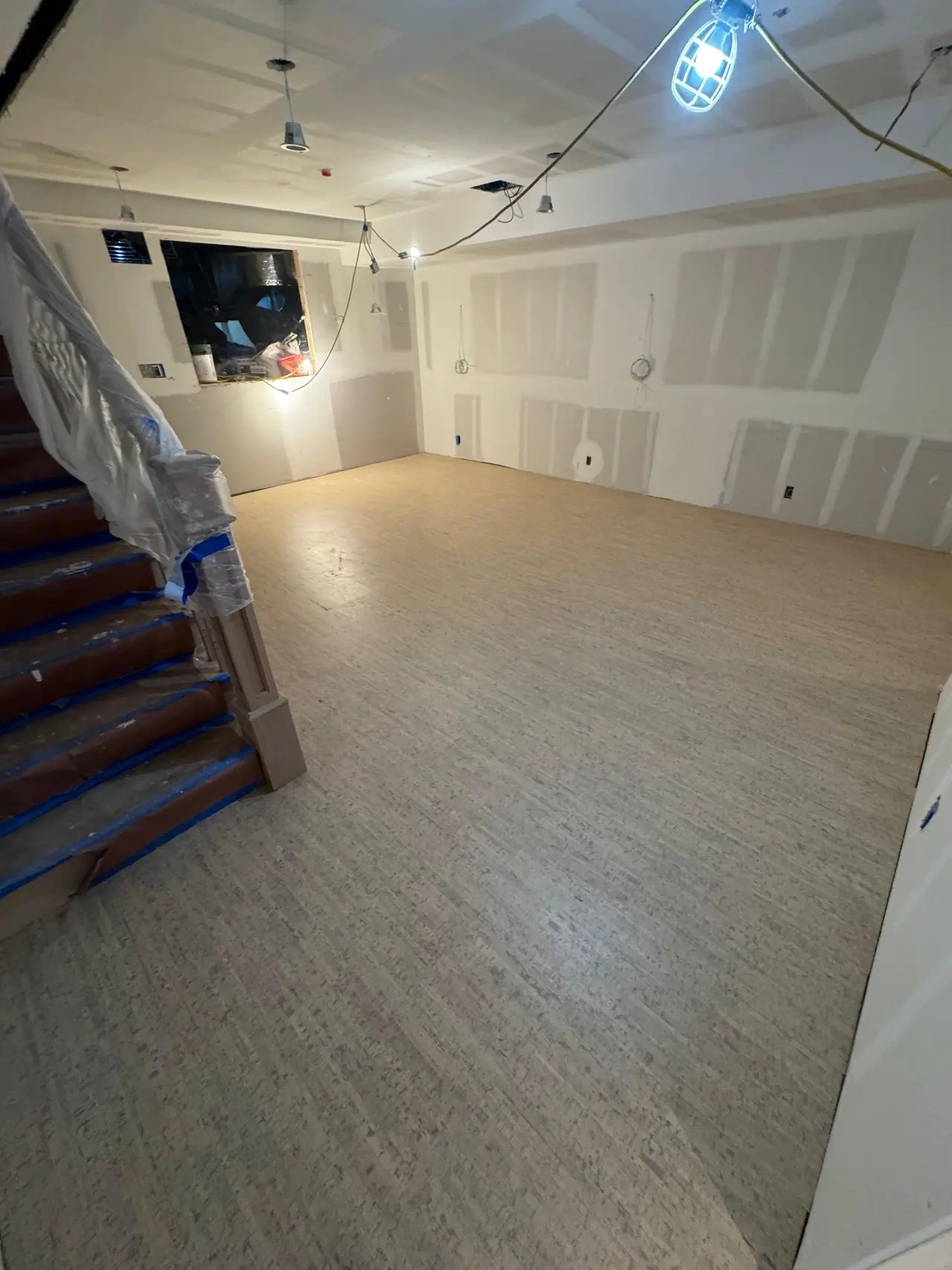 Light wood-look LVP flooring installed in finished basement with open stair landing. — 2