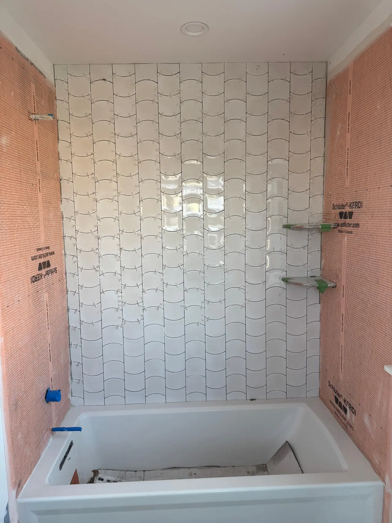 Full bathroom tile installation with wave-pattern wall tile, glass corner shelves, and tub surround. — 1