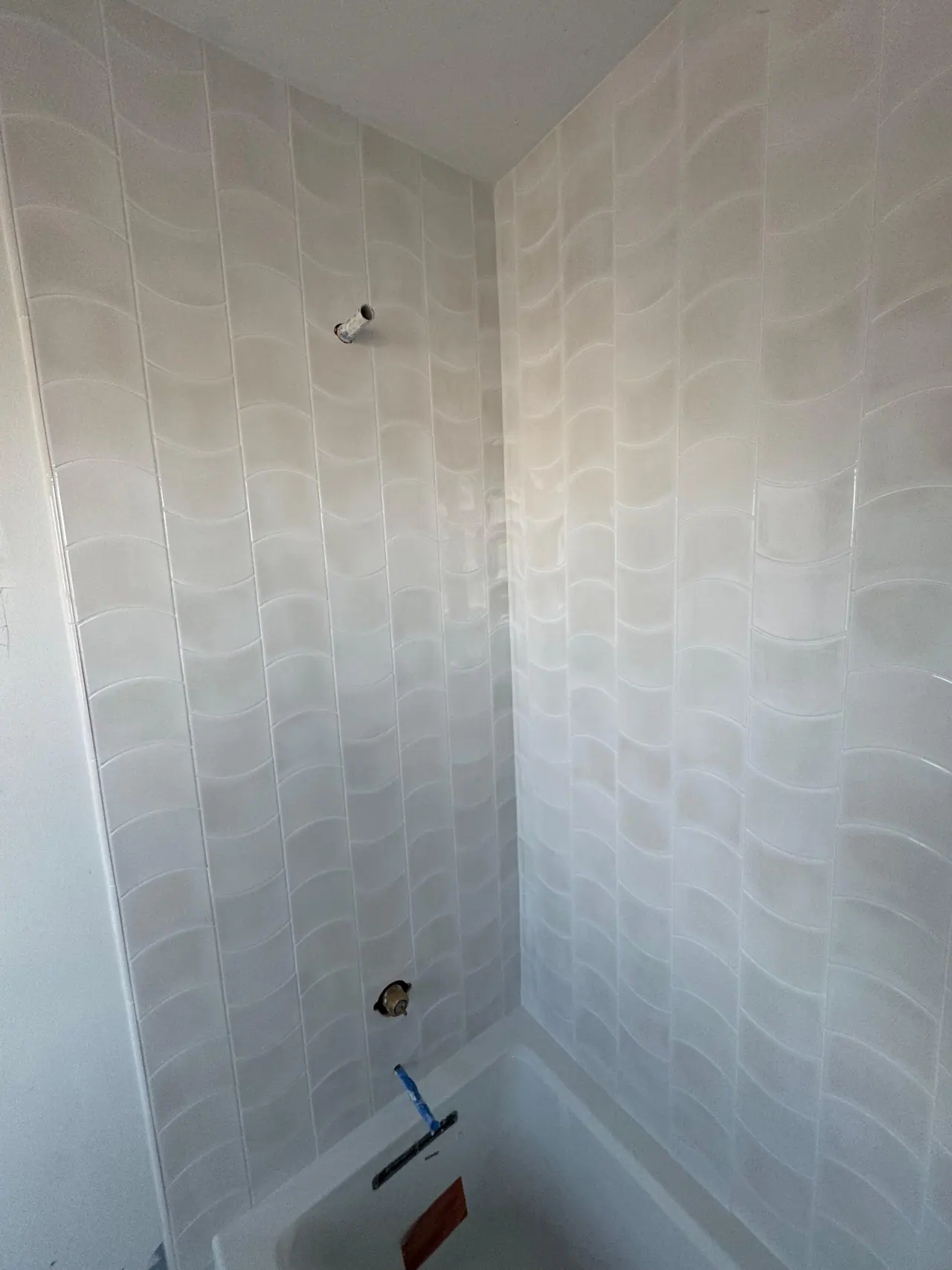 Full bathroom tile installation with wave-pattern wall tile, glass corner shelves, and tub surround. — 4
