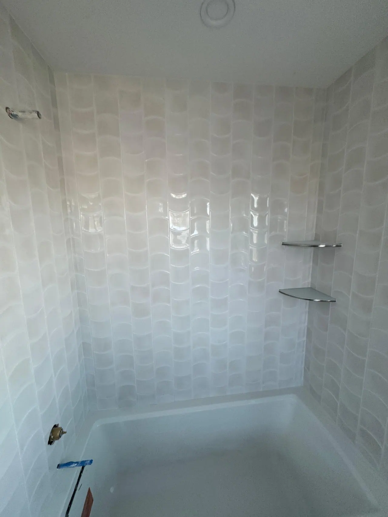 Full bathroom tile installation with wave-pattern wall tile, glass corner shelves, and tub surround. — 5